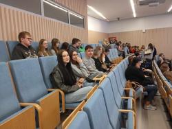 Uczniowie siedzą na widowni i słuchają wykładu