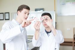 Dwóch uczniów oglądających przyrząd optyczny
